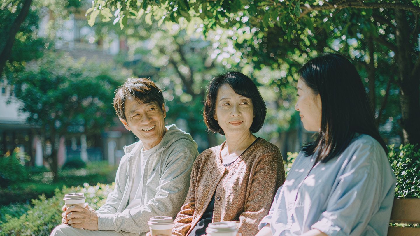 几位 50 多岁的朋友在城市公园长椅上从容交谈