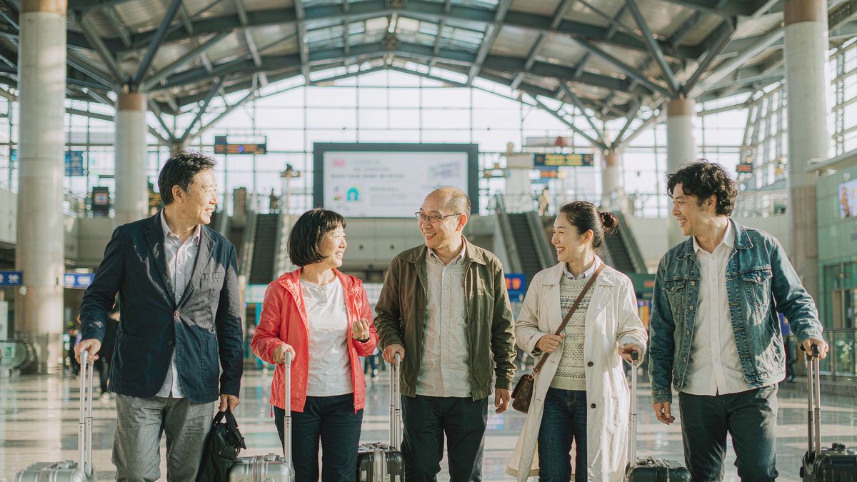 五位朋友拉着行李走进车站，准备出发旅行