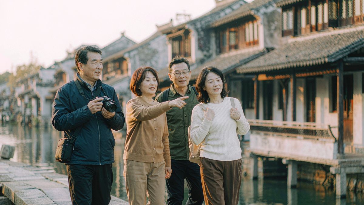 四位朋友在江南古镇边走边聊、拍照赏景